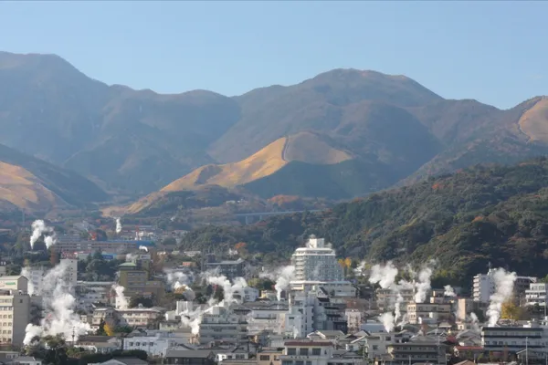 山々を背景に湯けむりが立ちのぼる別府の街並み