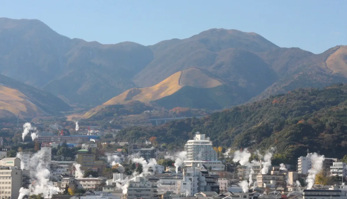山々を背景に湯けむりが立ちのぼる別府の街並み